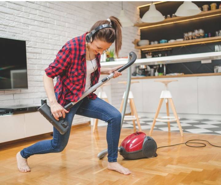 Young woman playing with vacuum cleaner